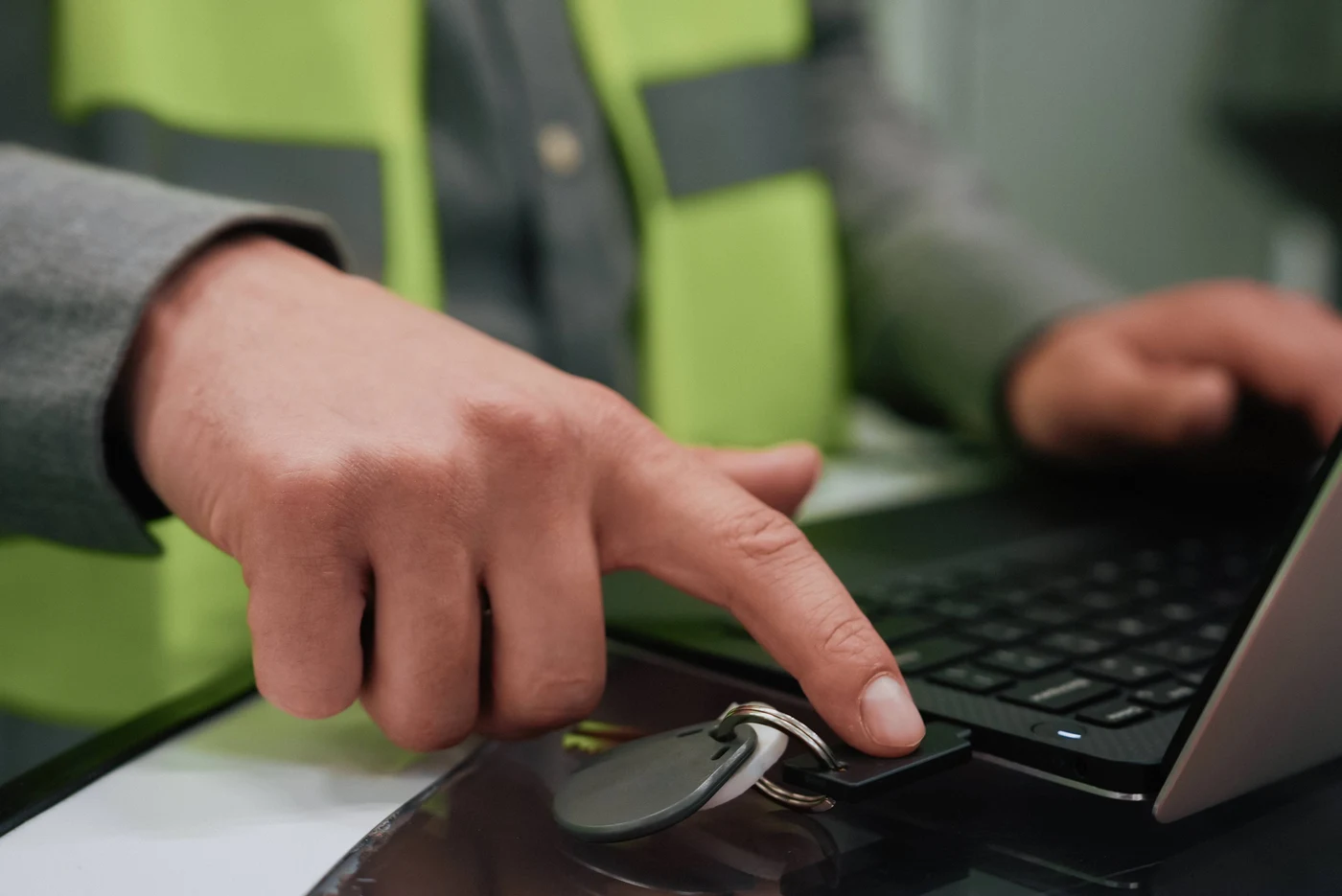 Djelatnik u reflektirajućem prsluku dodiruje YubiKey utaknut u prijenosnik