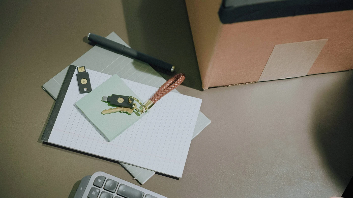 Dva ključa YubiKey na bilježnici: jedan na privjesku uz obični ključ, drugi odvojeno