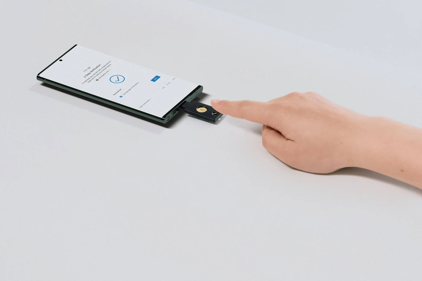 Prst dodiruje YubiKey u USB-C priključku Android mobitela na kojem Google traži potvrdu u dva koraka